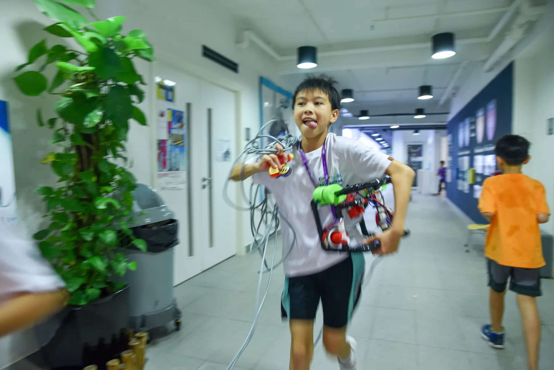 A student carrying a tethered underwater robot during a workshop